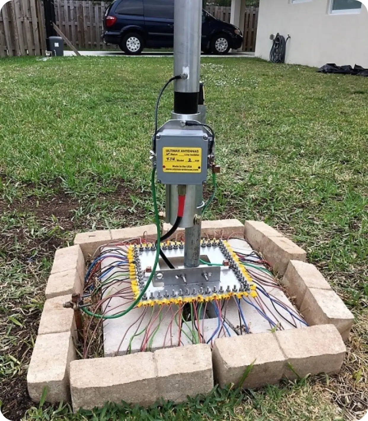 A pole with wires attached to it in the grass.